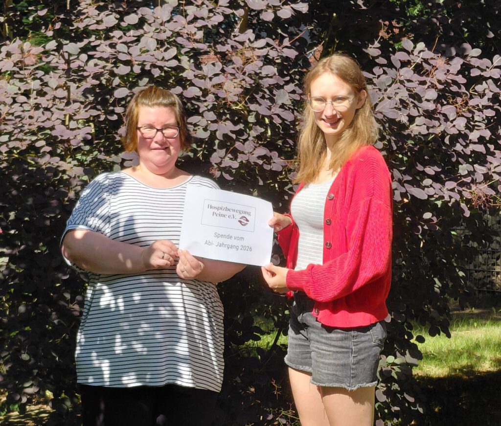 Frau Meyer-Hamann von der Hospizbewegung Peine und Frau Lina Schild vom Ratsgymnasium halten ein Spendenposter des Abi-Jahrgangs 2026.