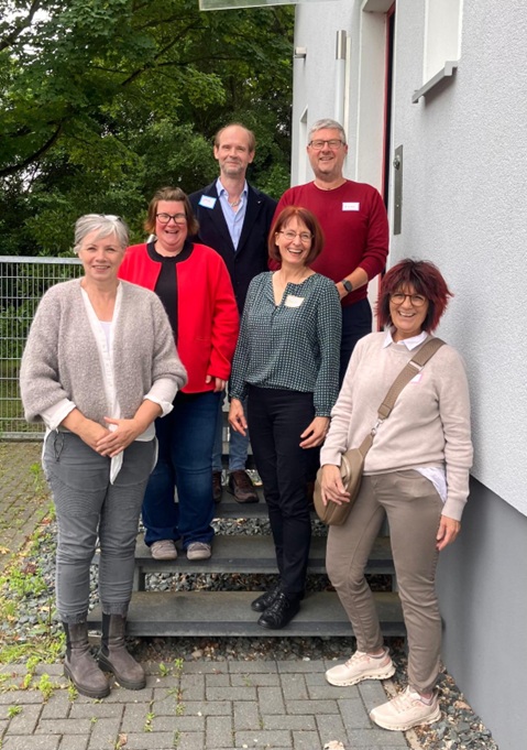 Gruppenfoto von fünf lächelnden Personen (drei Frauen und zwei Männer), die nebeneinander auf einer Treppe im Außenbereich stehen. Es handelt sich um die neuen ehrenamtlichen Sterbebegleiterinnen und Sterbebegleiter der Hospizbewegung Peine: Claudia Vennemann, Angela Klieme, Wiebke Helling, Jens Fröhlich und Andreas Köhler.